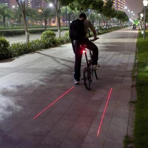 Cyclist riding at night with bright red bicycle tail light attached to helmet.  
