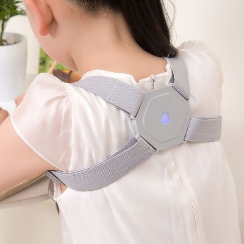 Person sitting at a desk wearing a discreet vibrating posture corrector harness.
